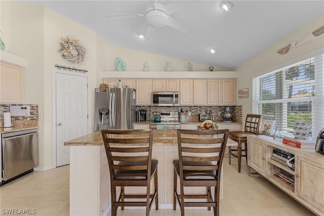 kitchen featuring a breakfast bar area, a kitchen island, light tile patterned flooring, and appliances with stainless steel finishes