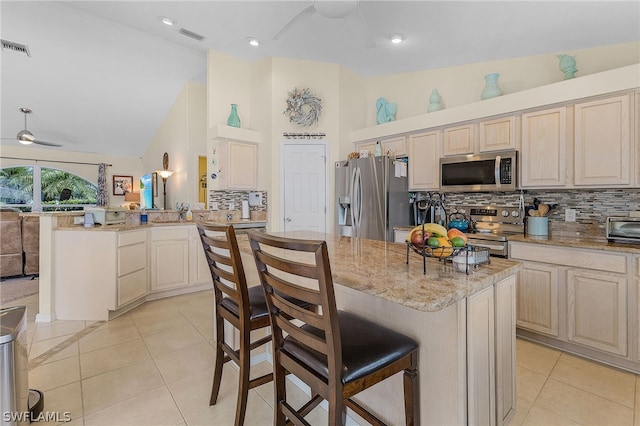 kitchen with kitchen peninsula, a kitchen breakfast bar, stainless steel appliances, high vaulted ceiling, and a center island