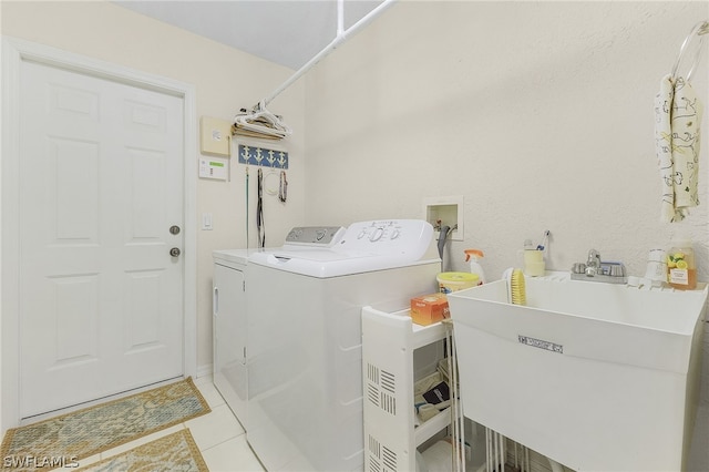 clothes washing area with washer and clothes dryer, light tile patterned floors, and sink