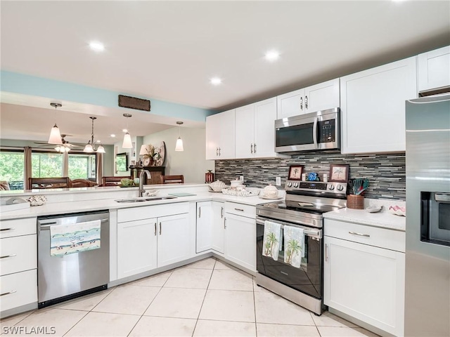 kitchen featuring kitchen peninsula, hanging light fixtures, sink, white cabinetry, and stainless steel appliances