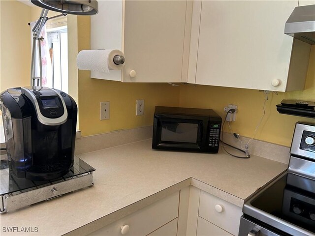 kitchen featuring white cabinets, stove, and exhaust hood