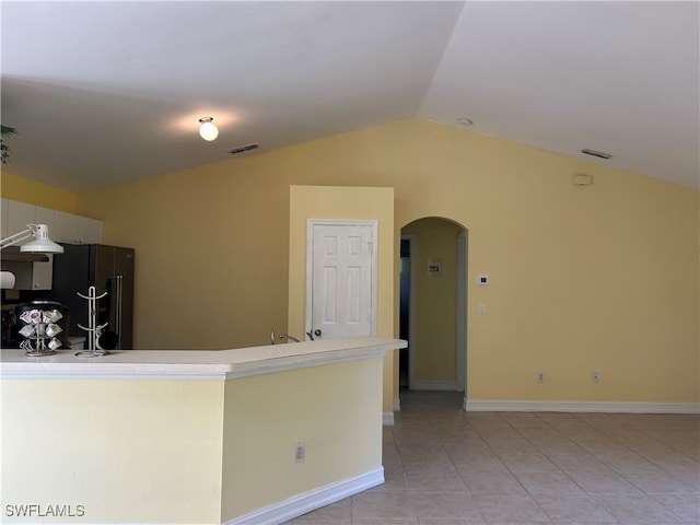 kitchen featuring vaulted ceiling, black refrigerator, and light tile patterned floors