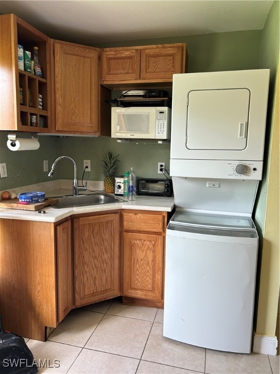 kitchen with stacked washer / drying machine, light tile patterned floors, and sink