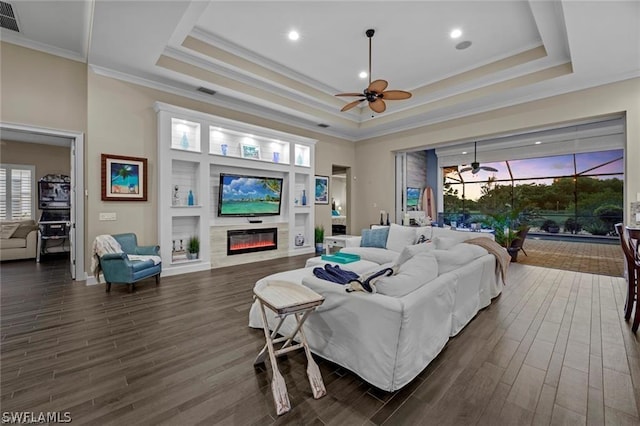 living room featuring a raised ceiling, ceiling fan, and dark hardwood / wood-style floors