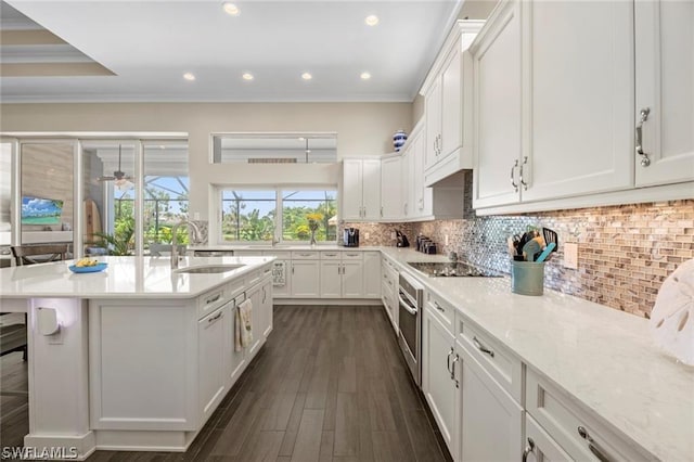 kitchen featuring decorative backsplash, white cabinetry, sink, and an island with sink