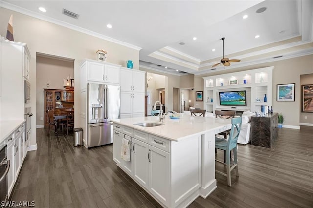 kitchen with a kitchen island with sink, a raised ceiling, sink, white cabinetry, and stainless steel appliances