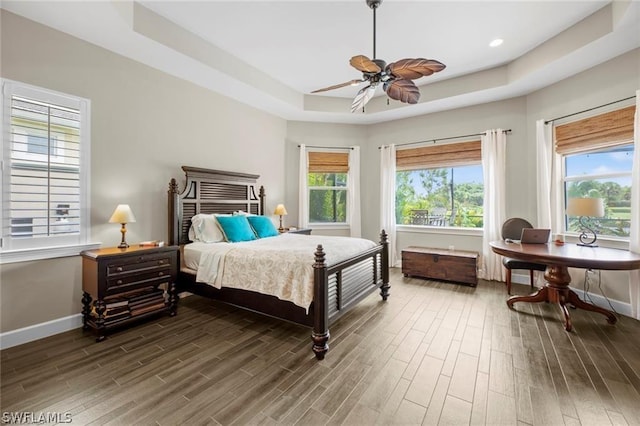 bedroom with a tray ceiling, multiple windows, and ceiling fan