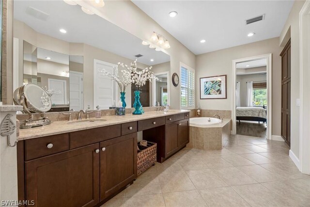 bathroom with tile patterned flooring, vanity, and tiled tub