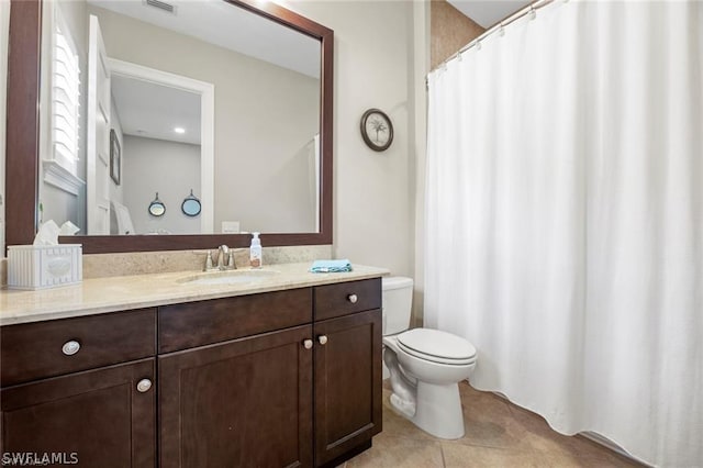 bathroom with toilet, vanity, and tile patterned floors