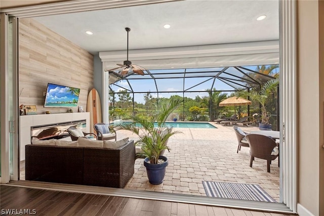 view of patio with glass enclosure, ceiling fan, and an outdoor living space