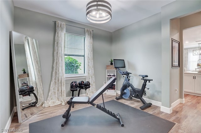 exercise room featuring light hardwood / wood-style floors and an inviting chandelier