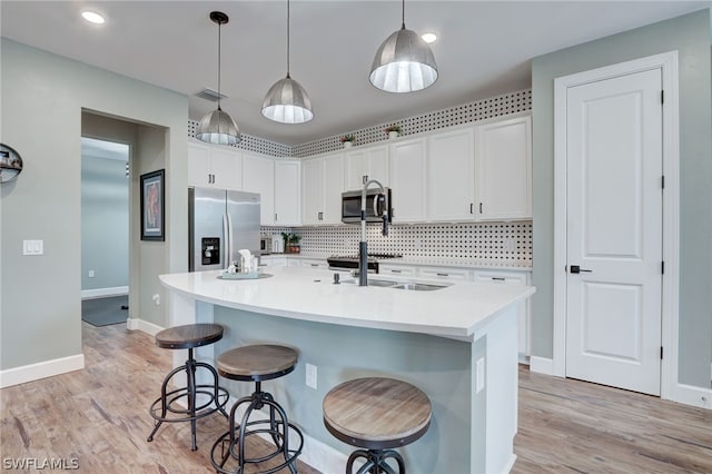 kitchen with pendant lighting, white cabinetry, a kitchen island with sink, and appliances with stainless steel finishes