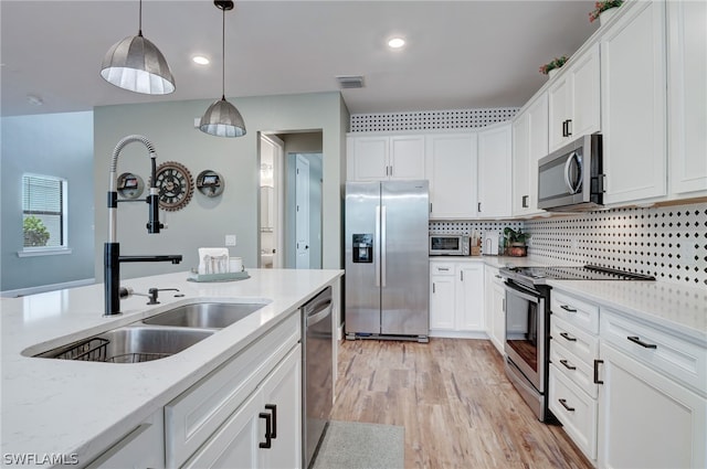 kitchen with white cabinetry, hanging light fixtures, light stone counters, and appliances with stainless steel finishes