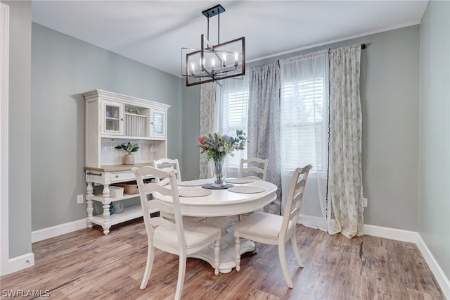 dining area with light wood-type flooring and an inviting chandelier