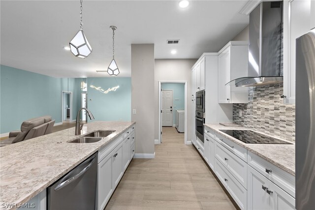 kitchen featuring wall chimney exhaust hood, stainless steel appliances, sink, decorative light fixtures, and white cabinetry