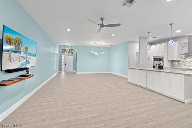 unfurnished living room with sink, ceiling fan, and light hardwood / wood-style flooring