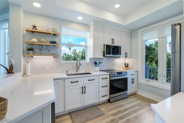 kitchen with sink, stainless steel appliances, light hardwood / wood-style flooring, decorative backsplash, and white cabinets