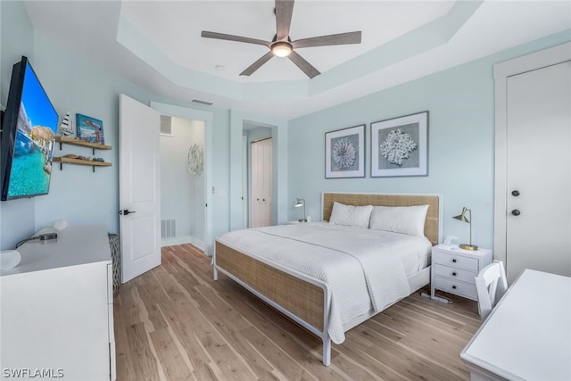 bedroom featuring a tray ceiling, ceiling fan, and light hardwood / wood-style floors