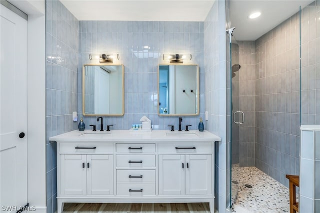 bathroom featuring hardwood / wood-style floors, vanity, a shower with shower door, and tile walls