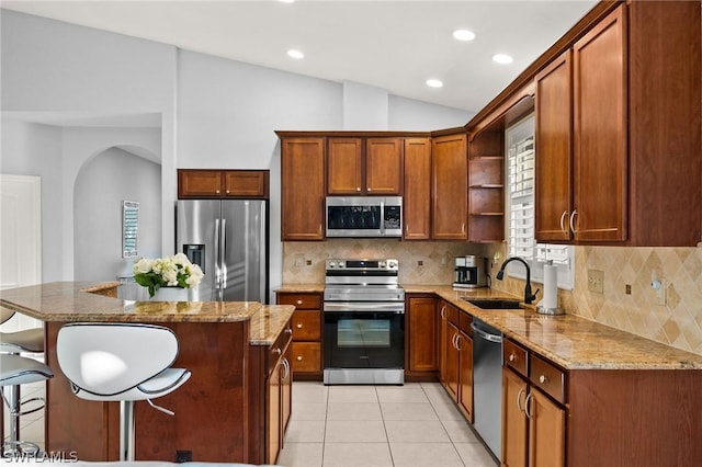 kitchen featuring a center island, sink, vaulted ceiling, light stone counters, and stainless steel appliances