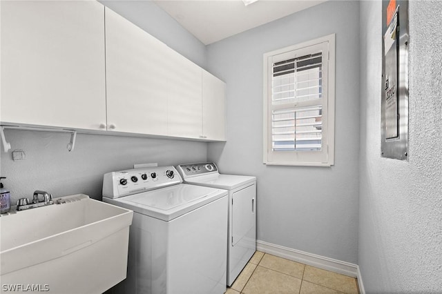 clothes washing area featuring light tile patterned flooring, cabinets, sink, and washing machine and clothes dryer