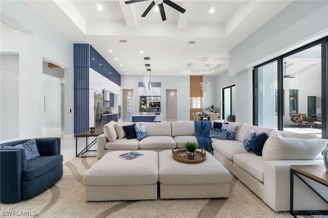 living room with a raised ceiling and ceiling fan