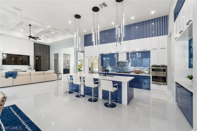 kitchen with decorative light fixtures, sink, white cabinets, a high ceiling, and a spacious island