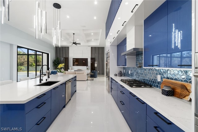 kitchen featuring sink, decorative light fixtures, blue cabinetry, and a center island with sink