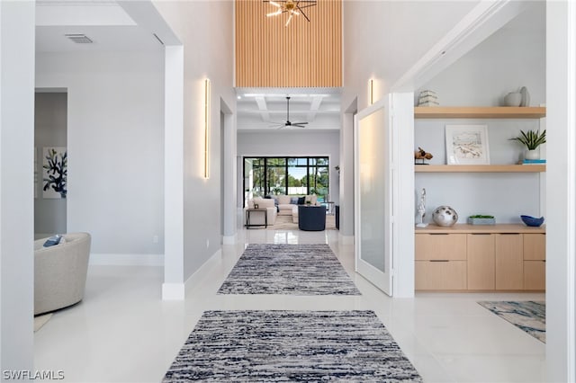 hall featuring beamed ceiling, coffered ceiling, built in features, and light tile patterned floors