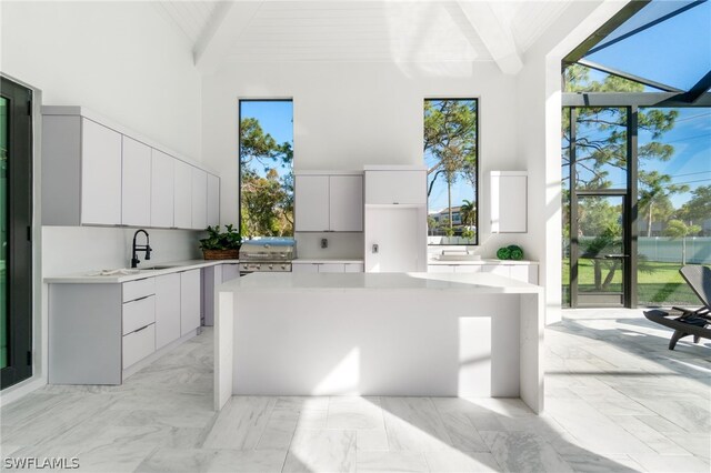 kitchen with sink, white cabinetry, high vaulted ceiling, a center island, and beamed ceiling