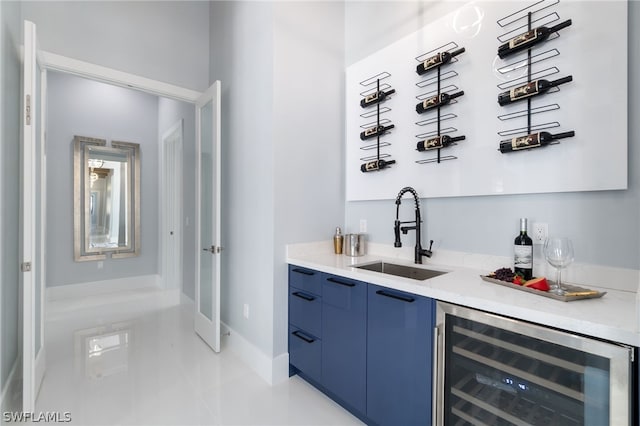 bar with wine cooler, blue cabinetry, and sink