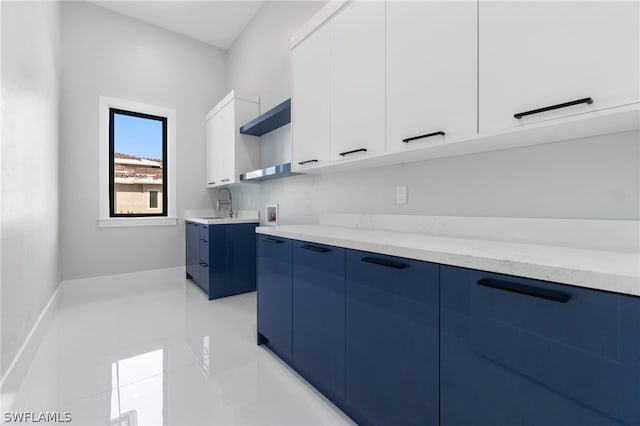 kitchen featuring sink, light tile patterned floors, white cabinetry, light stone countertops, and blue cabinets