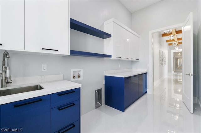 kitchen with white cabinetry, sink, and blue cabinets