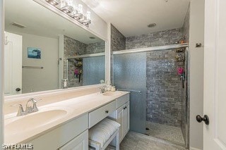 bathroom featuring a shower with shower door and dual bowl vanity