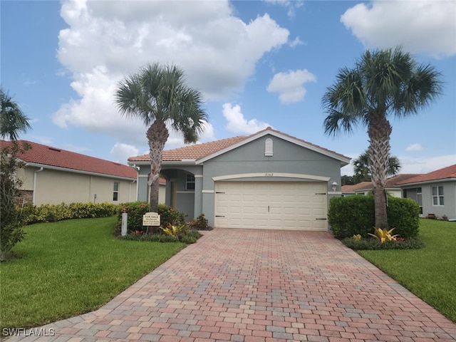 view of front of house with a tile roof, an attached garage, decorative driveway, a front lawn, and stucco siding