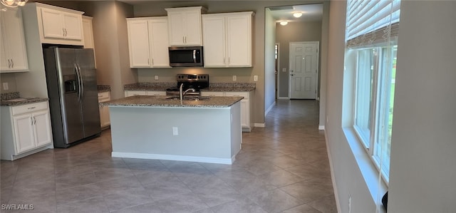 kitchen featuring appliances with stainless steel finishes, plenty of natural light, an island with sink, and light tile patterned floors