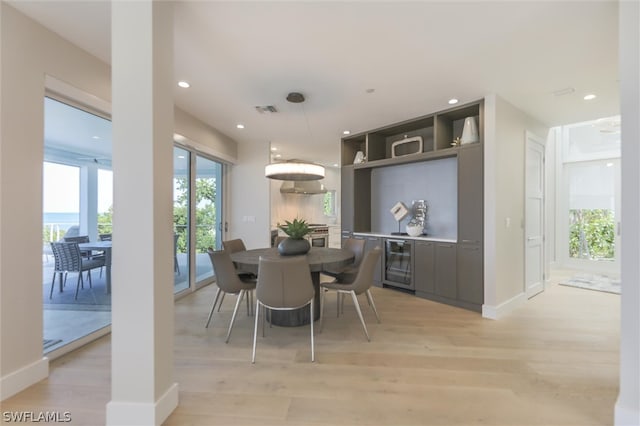 dining area with beverage cooler and light wood-type flooring