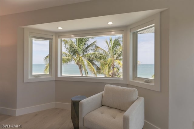 sitting room with a wealth of natural light, hardwood / wood-style flooring, and a water view