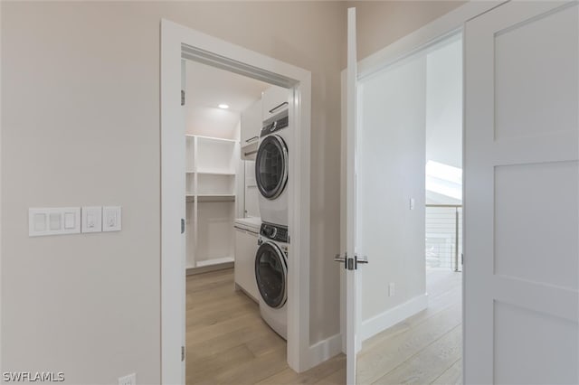 clothes washing area with light hardwood / wood-style flooring and stacked washer / dryer