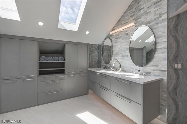 bathroom with backsplash, vanity with extensive cabinet space, double sink, and lofted ceiling with skylight