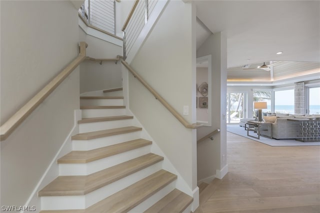 stairs featuring a tray ceiling and hardwood / wood-style floors