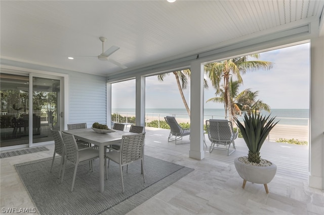 sunroom / solarium with ceiling fan and a water view