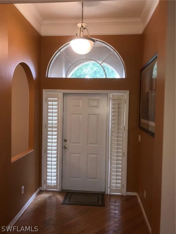 foyer entrance with crown molding and dark hardwood / wood-style flooring