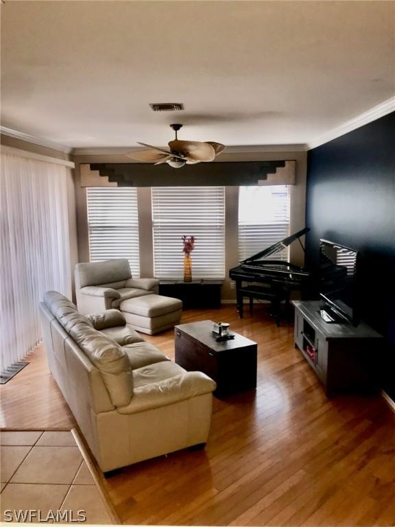 living room with light hardwood / wood-style floors, crown molding, and ceiling fan