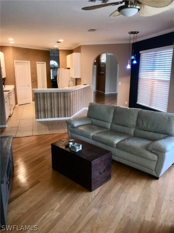 living room with crown molding, light hardwood / wood-style floors, and ceiling fan