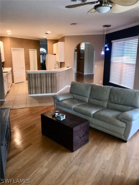 living room with ceiling fan, ornamental molding, and light hardwood / wood-style floors