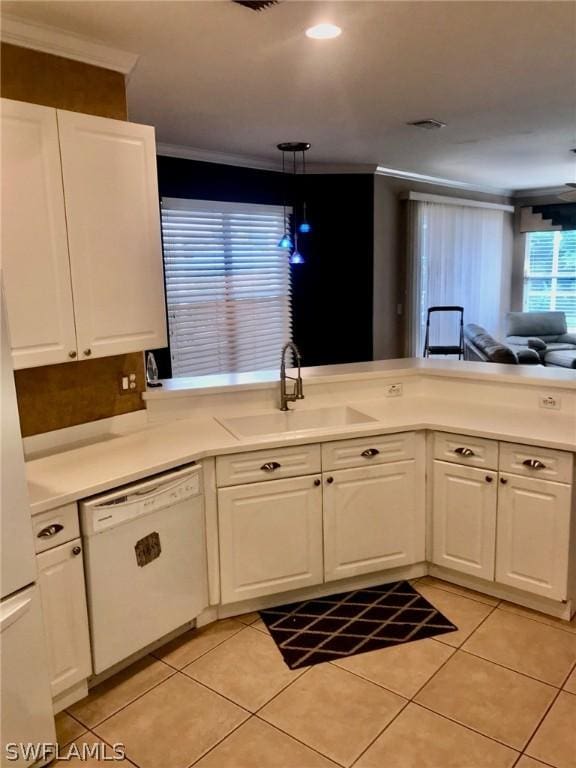 kitchen featuring light tile patterned floors, sink, white dishwasher, white cabinets, and hanging light fixtures