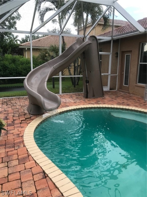 view of swimming pool featuring a water slide, a lanai, a patio area, and a playground