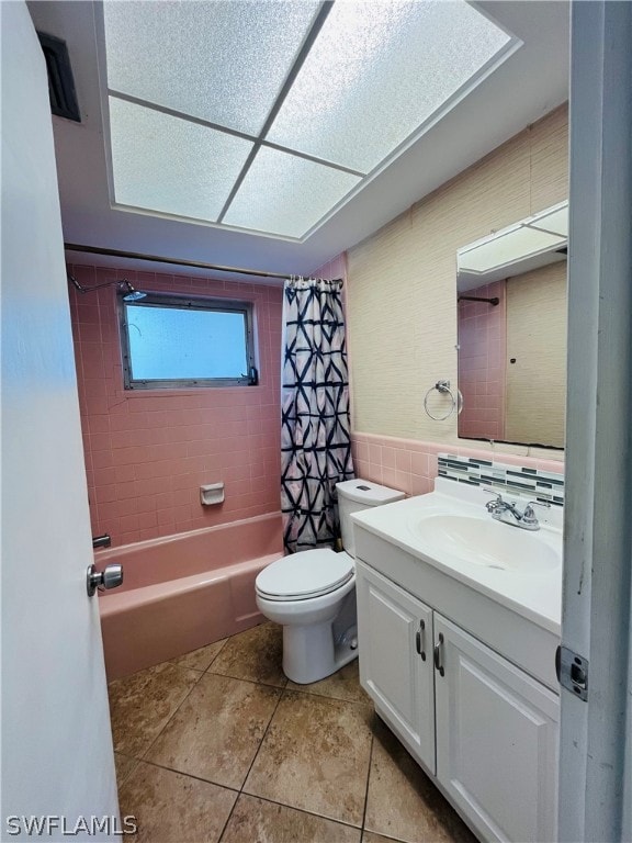 full bathroom with tile patterned floors, vanity, shower / bath combo with shower curtain, tile walls, and toilet