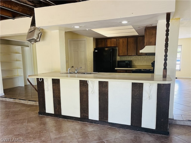 kitchen with sink, tasteful backsplash, kitchen peninsula, dark brown cabinets, and black appliances